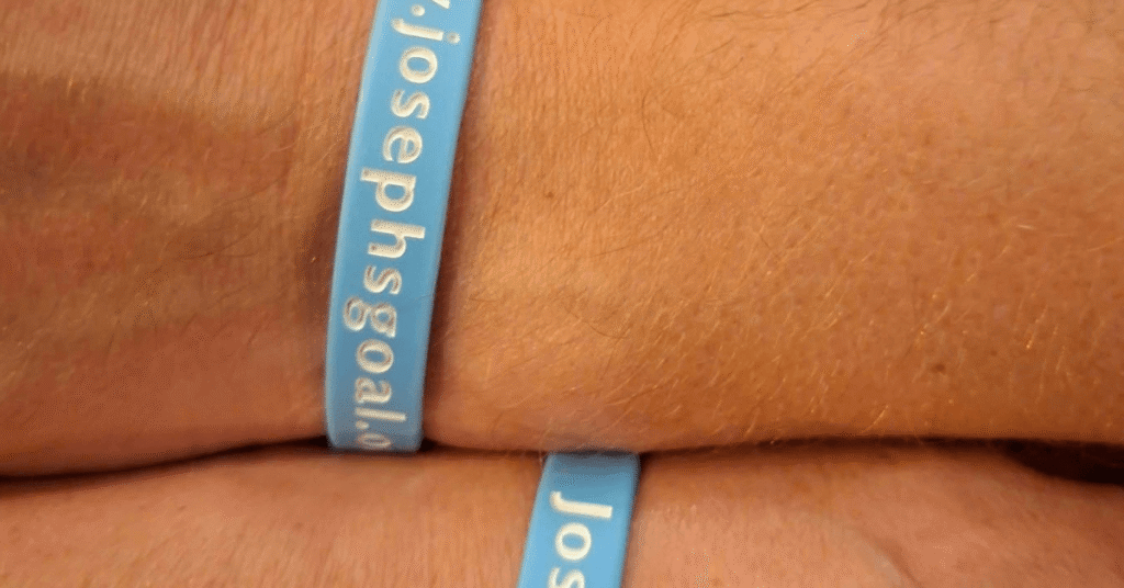 Close-up of a blue Joseph’s Goal wristband being worn around a person’s wrist.